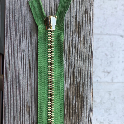 Zip metallo con nastro verde e ponte alzato.